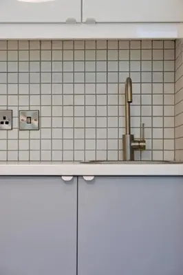 a kitchen with a sink and a white tiled wall at Fully licensed studio in peaceful neighbourhood in Edinburgh