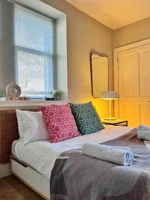 a bedroom with a bed with pillows and a mirror at Fully licensed studio in peaceful neighbourhood in Edinburgh