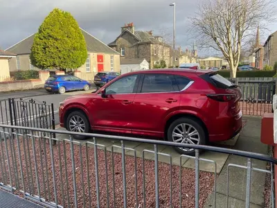 a red car parked in a parking lot at 3BR Sleeps 6 Free Parking Near Glasgow City in Renfrew