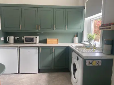 a kitchen with green cabinets and a washer and dryer at 3BR Sleeps 6 Free Parking Near Glasgow City in Renfrew