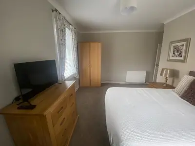 a bedroom with a bed and a flat screen tv at 3BR Sleeps 6 Free Parking Near Glasgow City in Renfrew