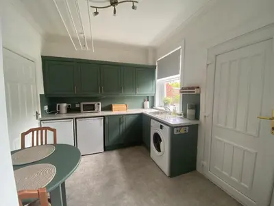 a kitchen with green cabinets and a table and a washing machine at 3BR Sleeps 6 Free Parking Near Glasgow City in Renfrew