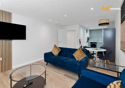 a living room with a blue couch and a table at Central 2BR Flat at Wellwynd I Parking Included in Airdrie