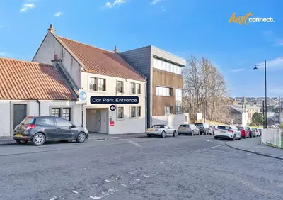 a parking lot with cars parked in front of a building at Central 2BR Flat at Wellwynd I Parking Included in Airdrie