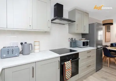 a kitchen with white cabinets and a stove top oven at Central 2BR Flat at Wellwynd I Parking Included in Airdrie
