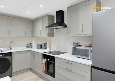 a kitchen with white cabinets and a refrigerator at Central 2BR Flat at Wellwynd I Parking Included in Airdrie