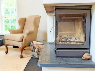 a living room with a fireplace and a chair at The Granary in Moffat