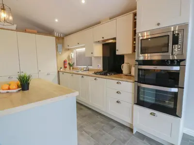 a kitchen with white cabinets and a stove top oven at Serenity Lodge in Wemyss Bay