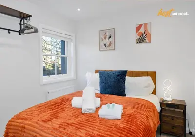 a bedroom with a large orange bed with towels on it at Comfy 1 Bed Airdrie Flat w Private Parking in Airdrie