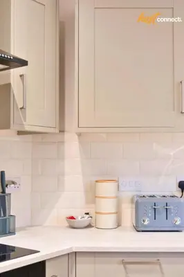 a kitchen with white cabinets and a blue toaster at Comfy 1 Bed Airdrie Flat w Private Parking in Airdrie