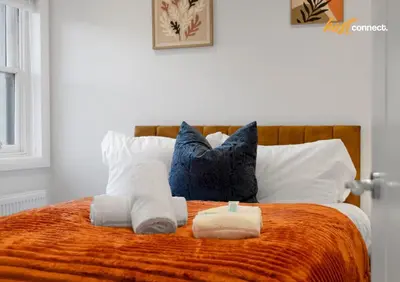 a bedroom with a bed with towels and pillows at Comfy 1 Bed Airdrie Flat w Private Parking in Airdrie