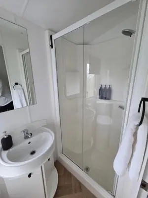 a white bathroom with a shower and a sink at Noah's Luxe Retreats in Newton Stewart
