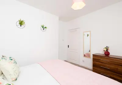 a white bedroom with a bed and a dresser at Broomfield No 31 by Klass Living Airdrie in Airdrie