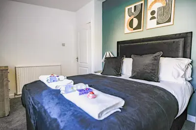 a bedroom with a large bed with towels on it at Elm House in Bathgate