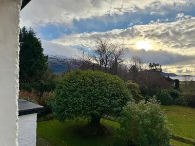 a tree in a yard with the sunset in the background at Lochview Flat in Onich