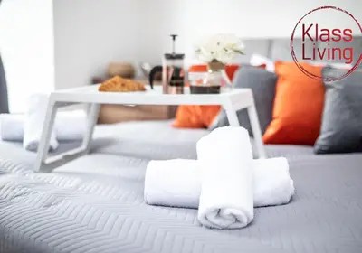 a pile of towels on a bed with a table at Cosy Apartment by Klass Living Bellshill in Bellshill