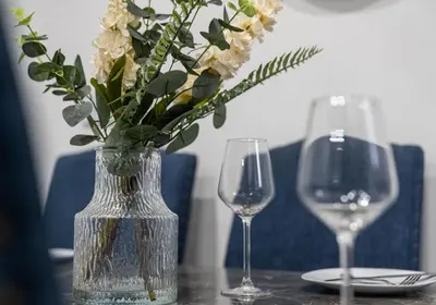 a table with two wine glasses and a vase with flowers at Elmbank Avenue House by Klass Living Uddingston in Uddingston