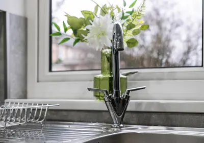 a kitchen sink with a vase of flowers on a window at Elmbank Avenue House by Klass Living Uddingston in Uddingston