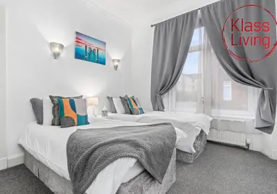two beds in a white room with a window at Elmbank Apartment by Klass Living Bellshill in Bellshill