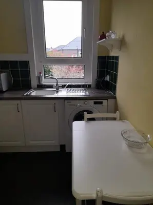 a kitchen with a sink and a table and a window at Celia's house in Stirling