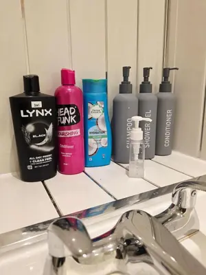 a bathroom counter with four bottles of shampoo and a sink at Cozy 2Bed Flat in Glasgow City Center in Glasgow