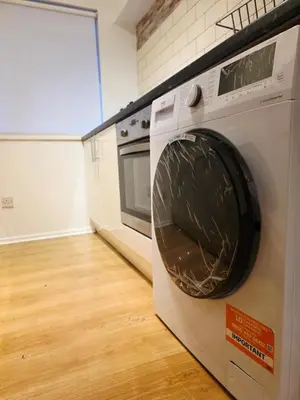 a washing machine is sitting in a kitchen at Cozy 2Bed Flat in Glasgow City Center in Glasgow