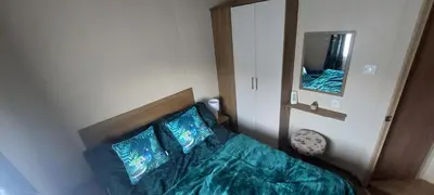 a bedroom with a bed with blue sheets and a mirror at BZ Green Haven Caravan in Ballantrae