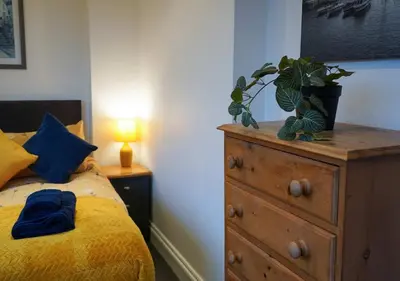 a bedroom with a bed and a dresser with a plant on it at Coppet Cove - 2 Bedroom Apartment - Saundersfoot in Moffat