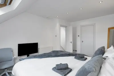 a white bedroom with a bed and a television at The Clydesider in Glasgow