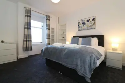 a bedroom with a large bed and a window at Modern 2 Bedroom Cottage Flat in Stenhousemuir