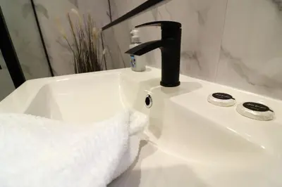 a bathroom sink with a towel and a faucet at Modern 2 Bedroom Cottage Flat in Stenhousemuir