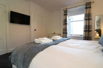 a bedroom with towels on a bed with a window at Modern 2 Bedroom Cottage Flat in Stenhousemuir