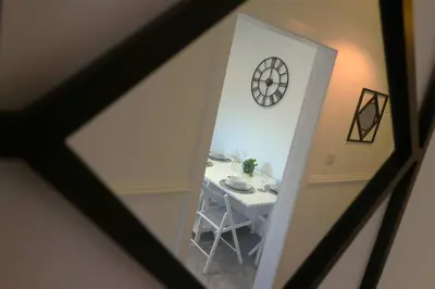 a room with a table and a clock on the wall at Modern 2 Bedroom Cottage Flat in Stenhousemuir
