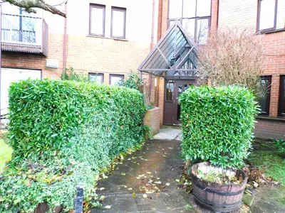 a house with green bushes in front of a building at Bright 3 Bed Apt overlooking the Clyde SEC & Hydro in Glasgow