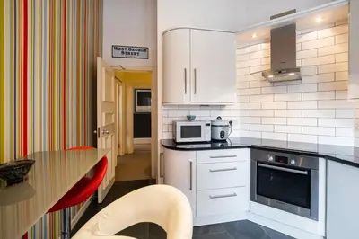 a kitchen with white cabinets and a table and a microwave at West George Street Apartment Glasgow in Glasgow