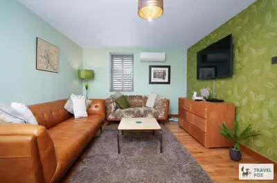 a living room with a leather couch and a tv at Charlotte Street Stay in Port Ellen