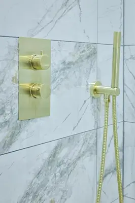 a shower with a gold switch on a wall at No 4 Burnbank in Oban