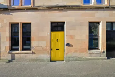 a yellow door on the side of a building at No 4 Burnbank in Oban
