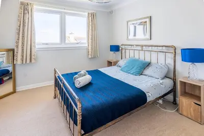 a bedroom with a bed with blue sheets and pillows at Scottish White House in Edinburgh