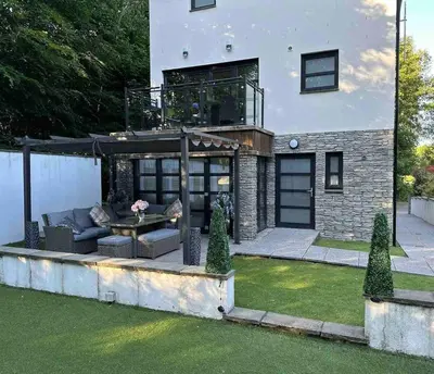 a house with a balcony with a table in a yard at The Loch Lomond Townhouse In The Centre of Balloch in Balloch