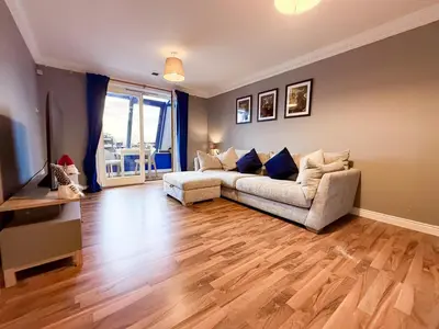 a living room with a couch and a wooden floor at Riverside 1bd - Balcony & Parking Hydro SECC in Glasgow