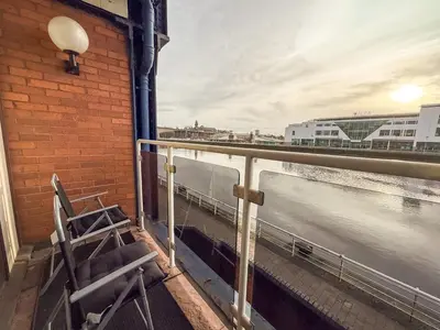a balcony with a chair and a view of the water at Riverside 1bd - Balcony & Parking Hydro SECC in Glasgow