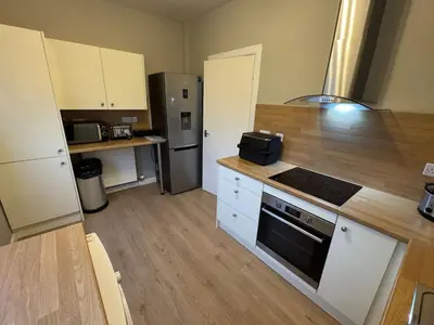 a kitchen with a stove and a refrigerator at Modern 2BR Cottage Flat in Bellshill