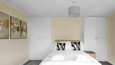a bedroom with a large white bed with pillows at Craigend Cottage in Rothesay