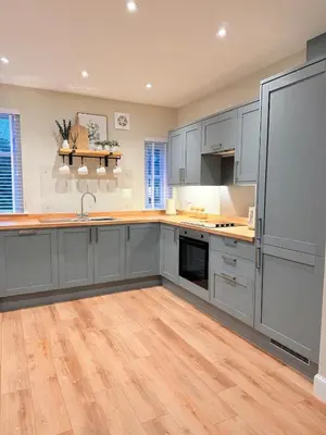 a kitchen with gray cabinets and a wooden floor at Bright and spacious 2 bedroom flat in Auchterarder
