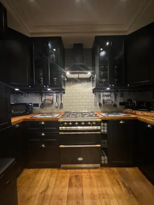 a kitchen with black cabinets and a stove at West London Boutique Apartment in Moffat