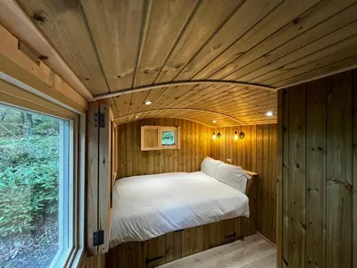 a bed in a wooden room with a window at Melfort House in Kilmelford