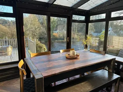 a dining room with a wooden table and large windows at Riverview House in Minnigaff