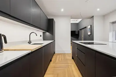 a kitchen with black cabinets and white counter tops at Spacious 5 Bedroom Home With 3 Bathrooms And Private Parking in Glasgow