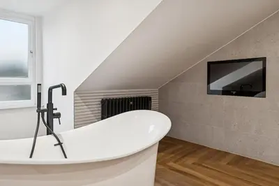 a bathroom with a bath tub and a tv at Spacious 5 Bedroom Home With 3 Bathrooms And Private Parking in Glasgow